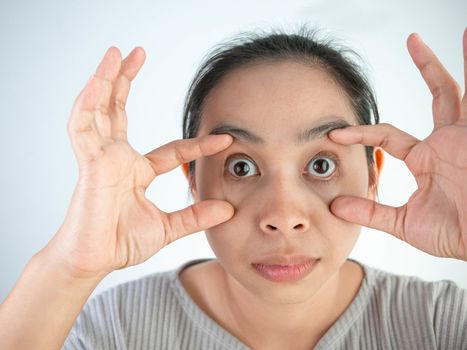 Asian woman is suffering of eye pain isolatedon grey background. Health care concept.