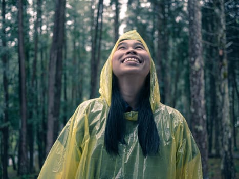 Portrait of Happy Asian woman wearing yellow raincoat stand in rain.