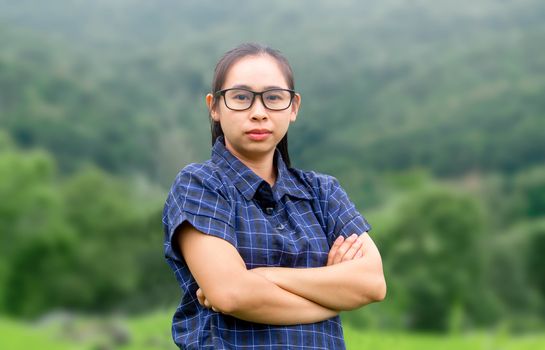 Asian farmer woman smile and cross one's arms with a look of proud on rice field background.