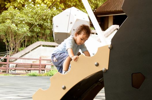 Asian little child girl having fun on a playground outdoors in summer.