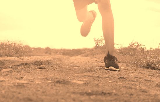 Close-up Legs of Asian young man is jogging on dirt road in the park. Healthy lifestyle.