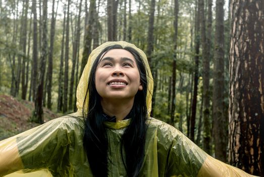 Portrait of Happy Asian woman wearing yellow raincoat stand in rain.