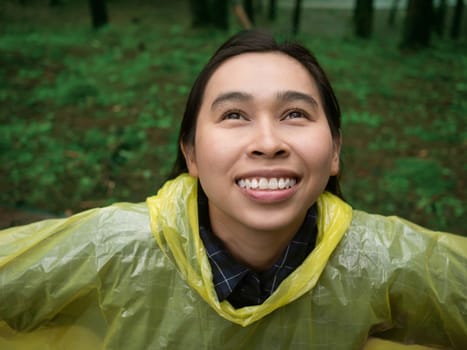 Portrait of Happy Asian woman wearing yellow raincoat stand in rain.