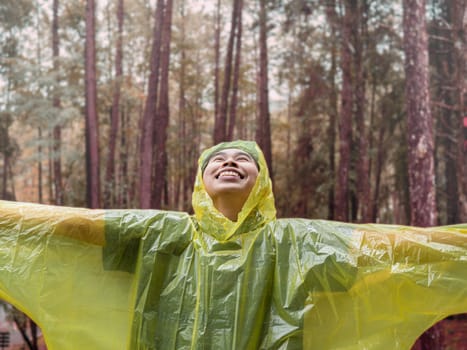 Portrait of Happy Asian woman wearing yellow raincoat stand in rain.