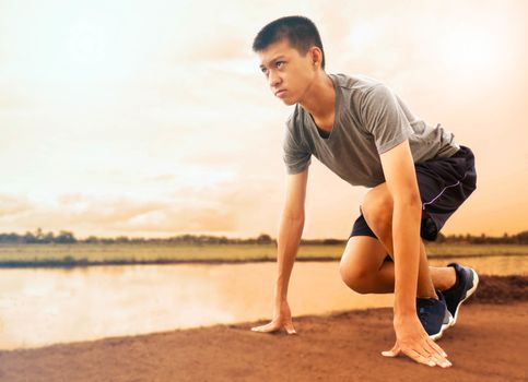 Fit and confident Asian young man in starting position ready for running. Healthy lifestyle.