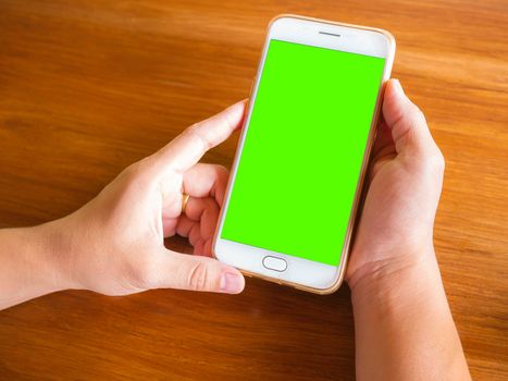 Close up of hand holding smartphone over wooden table background with space for your text.