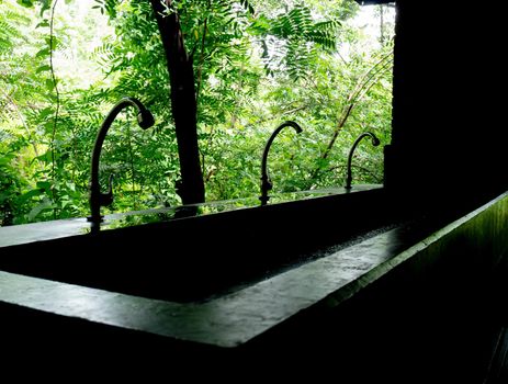 Row of the faucet to wash hands in cement sink in public toilets.