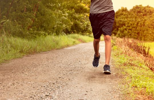 Close-up Legs of Asian young man is jogging on dirt road in the park. Healthy lifestyle.