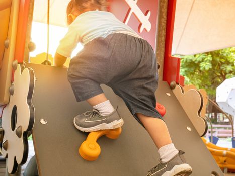 Asian little child girl climbing to slide at playground.