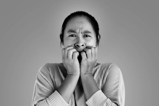 Asian woman frightened shocked what she see and holding hands near mouth, Isolated on dark background.