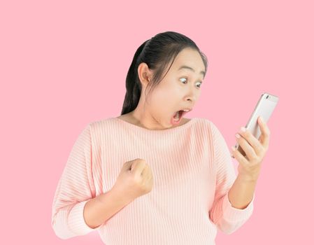 Asian woman shocked what she see in the smartphone and made a gesture of success, Isolated on pink background.