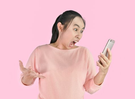 Asian woman angry and furious what she see in the smartphone, Isolated on pink background.