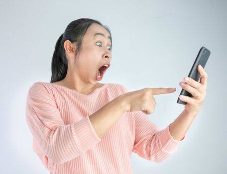 Asian woman shocked what she see in the smartphone and pointing it, Isolated on white background.