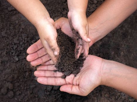 Close up of Woman and her child holding soil in hands. Environmental concept.