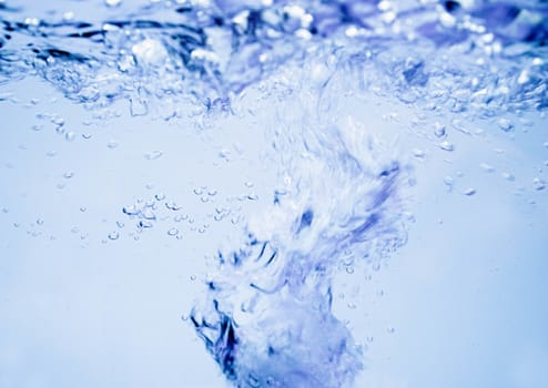 Air bubbles rising up to surface in blue pure water. Abstract background.