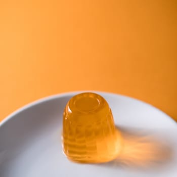 Close up of a orange gelatin on a white plate. Orange background.