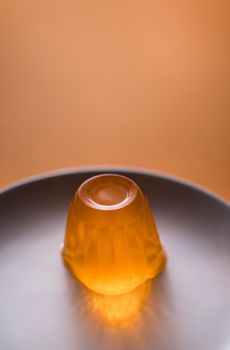 Close up of a orange gelatin on a white plate. Orange background.