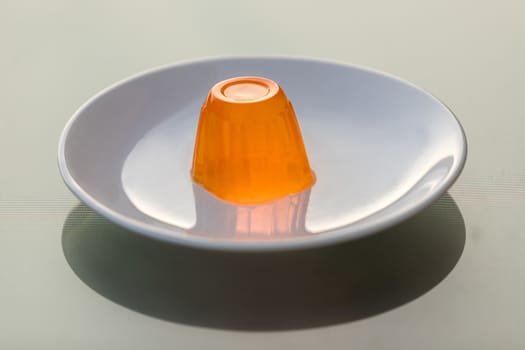 Close up of a orange gelatin on a white plate.