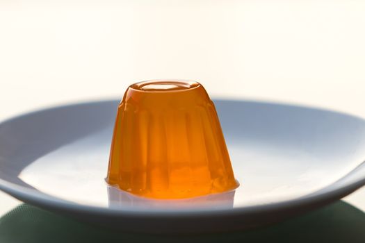 Close up of a orange gelatin on a white plate.