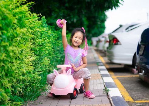 Asian little girl enjoys playing car on footpath