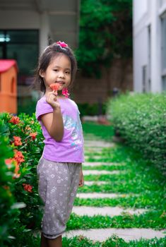 portrait of cute little girl with red flower standing in the park