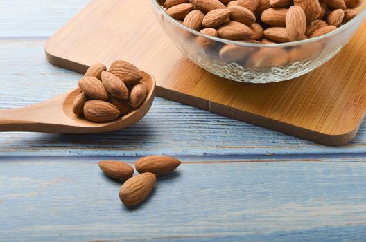 Almond nuts in a glass bowl on a wooden background. Selective focus.