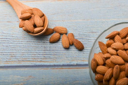 Almond nuts in a glass bowl on a wooden background. Selective focus.