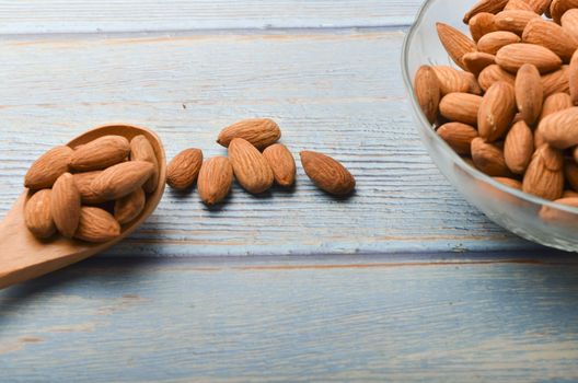 Almond nuts in a glass bowl on a wooden background. Selective focus.