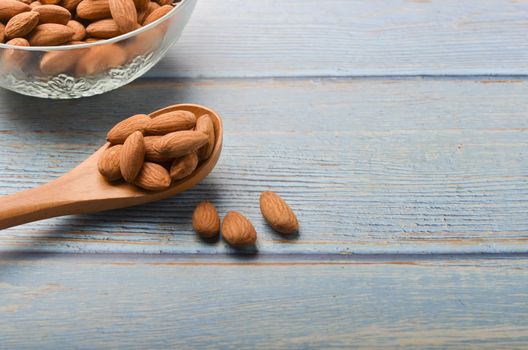 Almond nuts in a glass bowl on a wooden background. Selective focus.