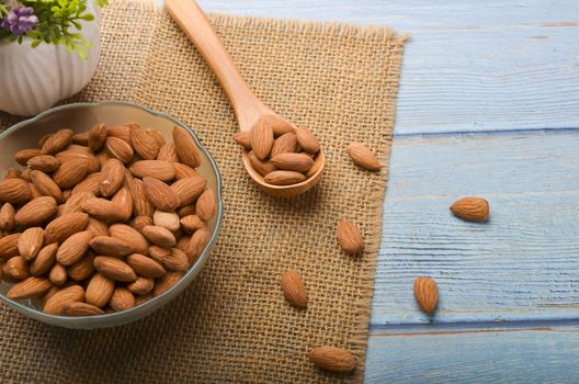 Almond nuts in a glass bowl on a wooden background. Selective focus.