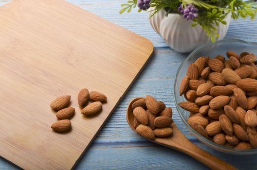 Almond nuts in a glass bowl on a wooden background. Selective focus.