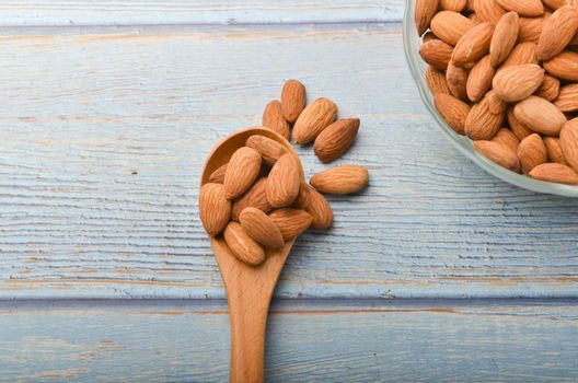 Almond nuts in a glass bowl on a wooden background. Selective focus.