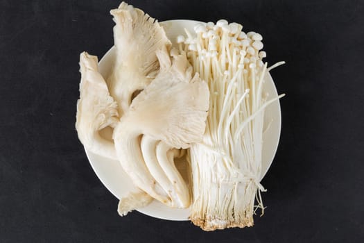 Various kinds of mushroom in a plate on black background.