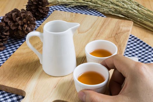 Hand Taking Tea Cup on Wood Texture Background