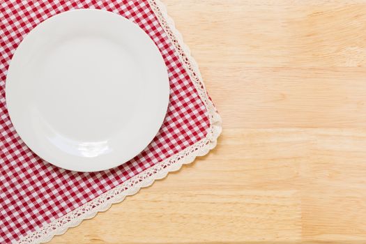 Empty plate without spoon and fork on table background.