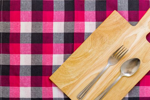 Empty plate with spoon and fork on table background.