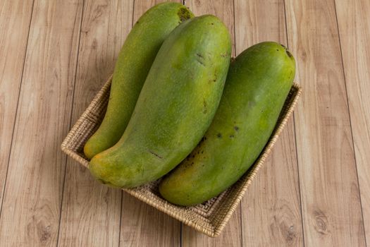 Mangoes from Thailand put in a basket on wood background.