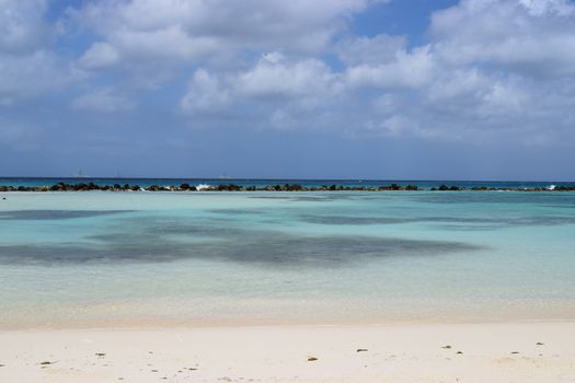 Aruba, Renaissance Island, Caribbean Sea. Sunny beach with white sand, coconut palm trees and turquoise sea. Summer vacation, tropical beach and pink flamingos