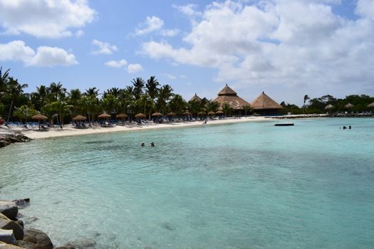 Aruba, Renaissance Island, Caribbean Sea. Sunny beach with white sand, coconut palm trees and turquoise sea. Summer vacation, tropical beach and pink flamingos