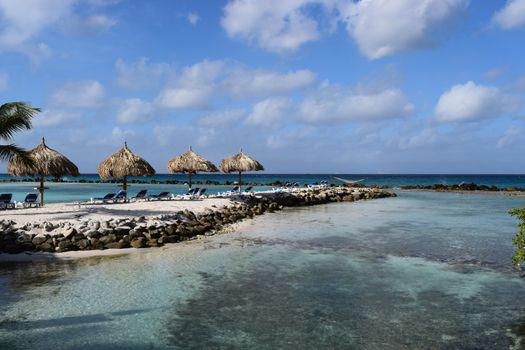 Aruba, Renaissance Island, Caribbean Sea. Sunny beach with white sand, coconut palm trees and turquoise sea. Summer vacation, tropical beach and pink flamingos