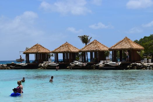 Aruba, Renaissance Island, Caribbean Sea. Sunny beach with white sand, coconut palm trees and turquoise sea. Summer vacation, tropical beach and pink flamingos