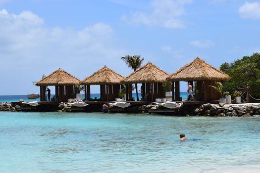 Aruba, Renaissance Island, Caribbean Sea. Sunny beach with white sand, coconut palm trees and turquoise sea. Summer vacation, tropical beach and pink flamingos