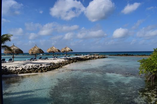 Aruba, Renaissance Island, Caribbean Sea. Sunny beach with white sand, coconut palm trees and turquoise sea. Summer vacation, tropical beach and pink flamingos