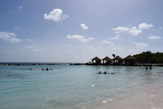 Aruba, Renaissance Island, Caribbean Sea. Sunny beach with white sand, coconut palm trees and turquoise sea. Summer vacation, tropical beach and pink flamingos