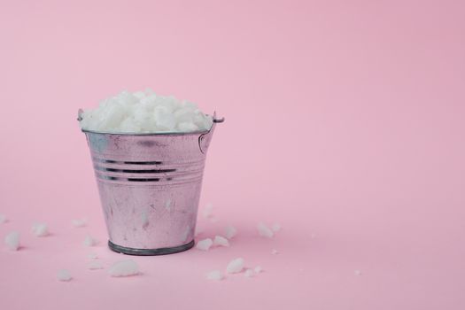 Sea salt in a tin bucket on pink background for seasoning or preserving food