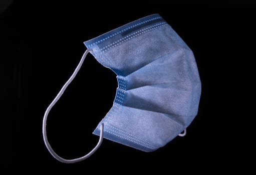 Simple blue standard surgical mask isolated on black