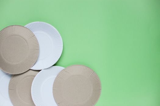 The layout on a green background from paper disposable plates. Caring for the environment. Recycling and sorting of garbage. Disposable tableware.