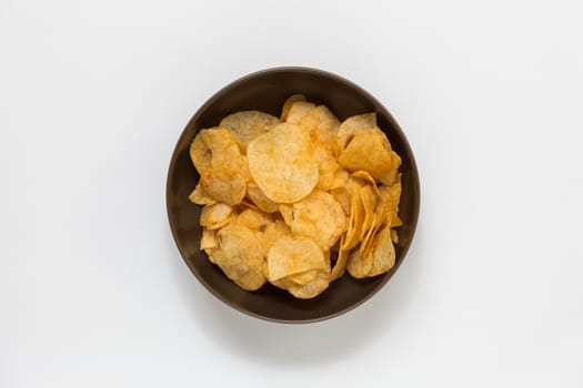 Crispy potato chips in a big brown bowl on white background.