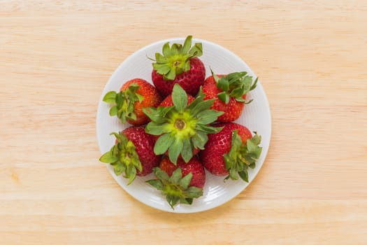 Strawberry in white plate on wooden background