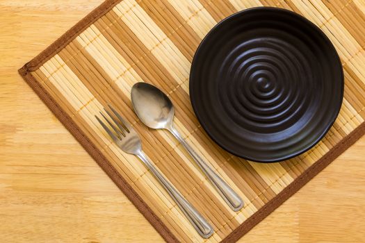 Empty plate with spoon and fork on table background.